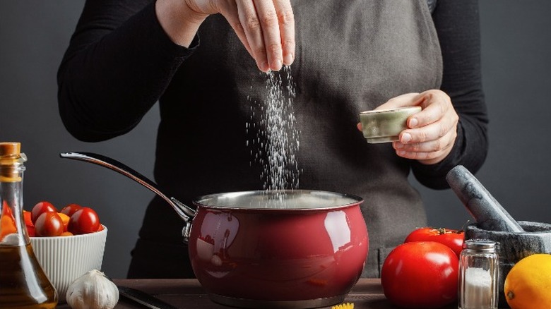 Person sprinkling salt in to pot