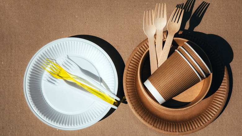 A set of paper utensils, wooden cutlery and plastic utensils on a brown background