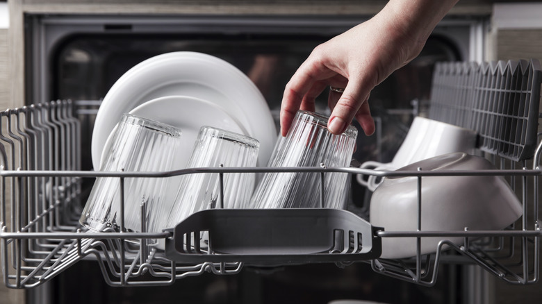 Person's hand loading dishwasher