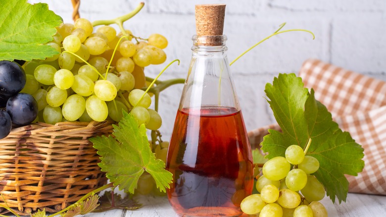 Glass bottle of red vinegar with white grapes
