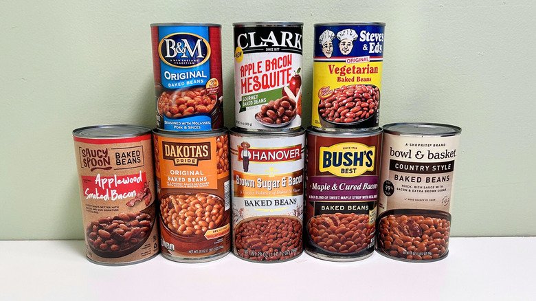 Eight cans of baked beans from various brands