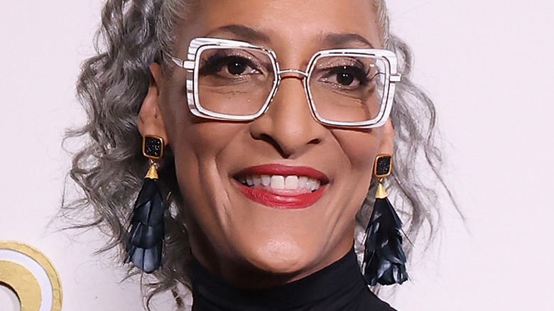 Carla Hall with clear glasses and wide smile