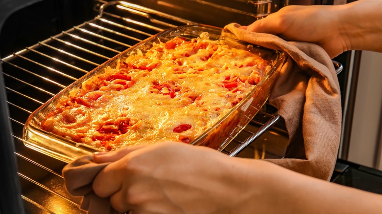person removing casserole from oven