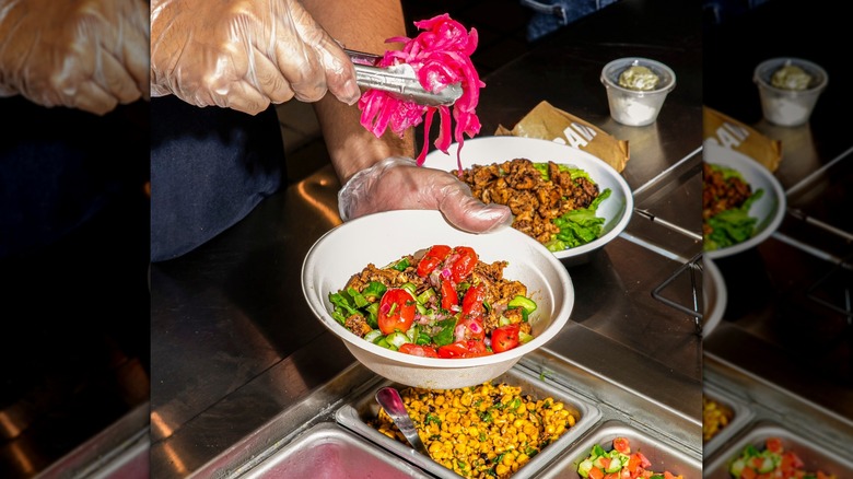 Adding picked onions to a bowl of meat and vegetables from Cava