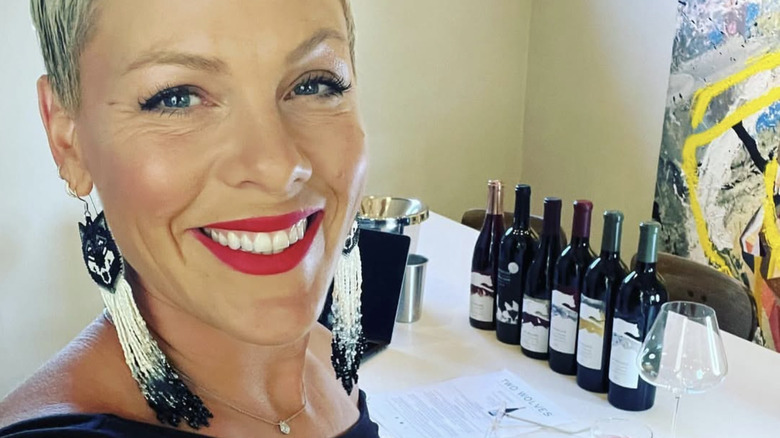 Alecia Moore aka Pink standing at a table with bottles of her wines