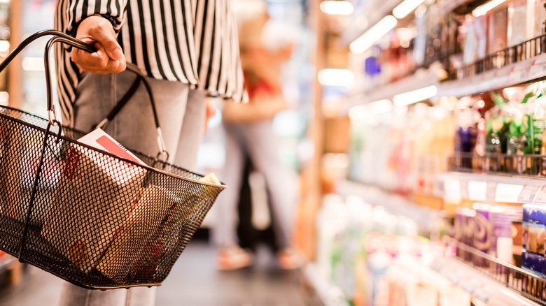 Woman with grocery basket looking at food to purchase