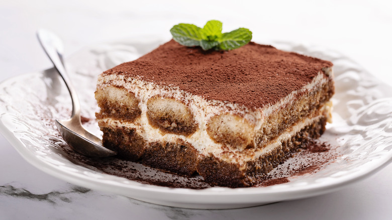 Tiramisu on a white plate with spoon