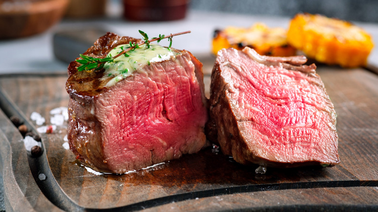 A filet mignon steak, cooked rare and topped with herbs and butter