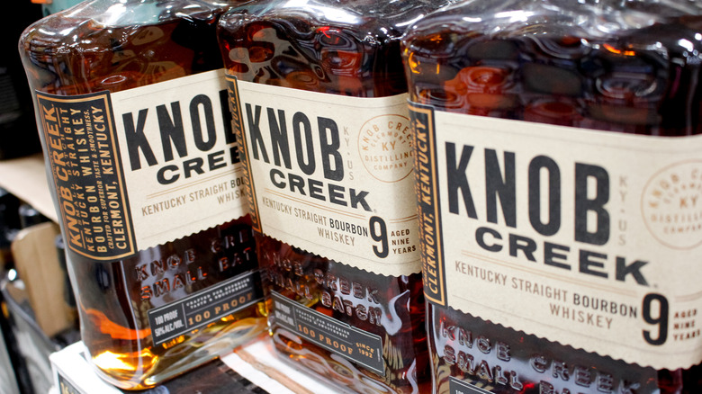 Knob Creek Single Barrel bourbon bottle next to empty bourbon glass with ice cubes