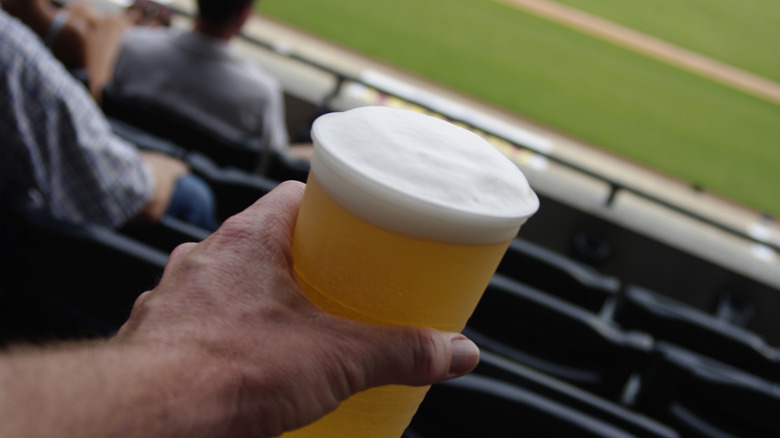Closeup of a beer in a man's hand at a baseball game