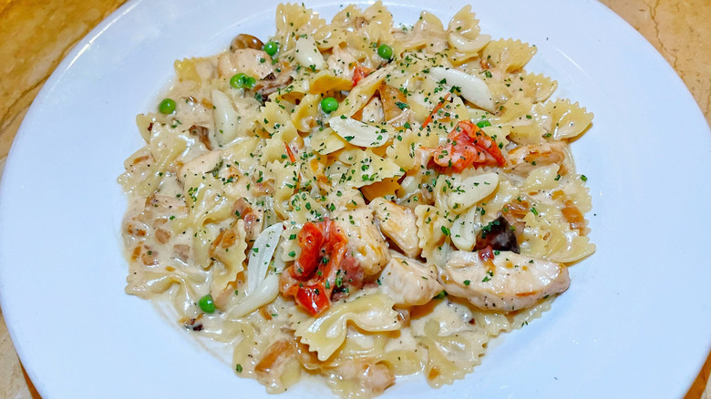 A bowl of farfalle with chicken and roasted garlic pasta garnished with parsley