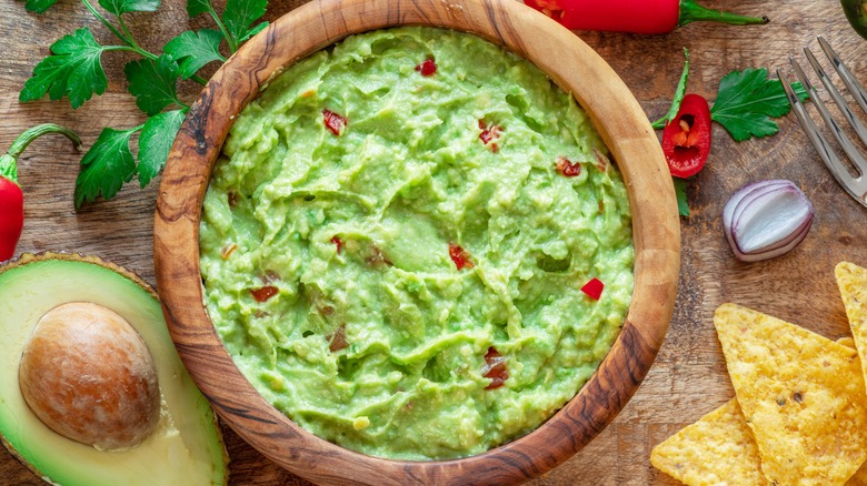 guacamole in wooden bowl with chips and cilantro