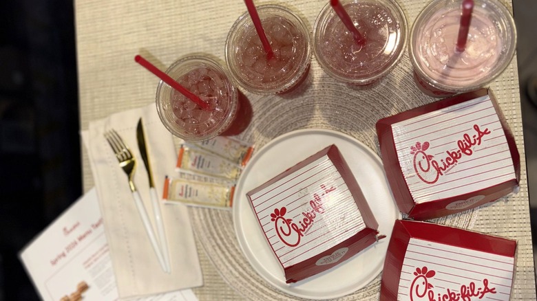An eagle-eyed view of four chick-fil-a drinks and three sandwiches in boxes