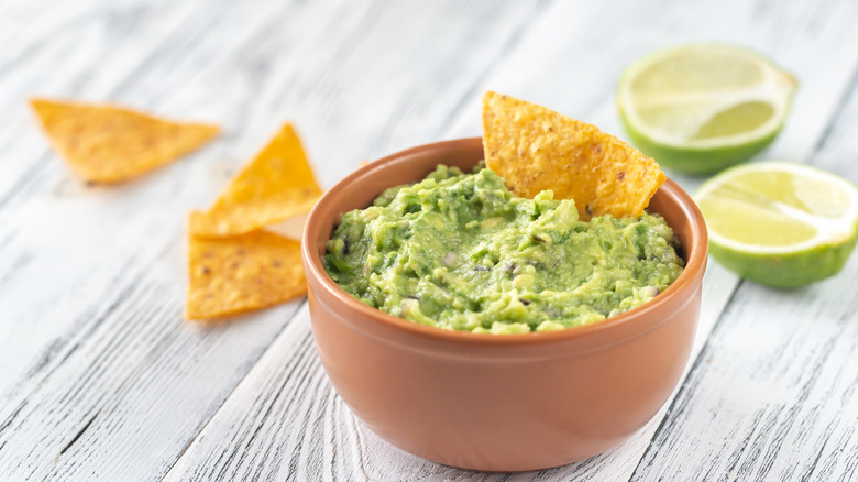 bowl of guacamole with a chip in it