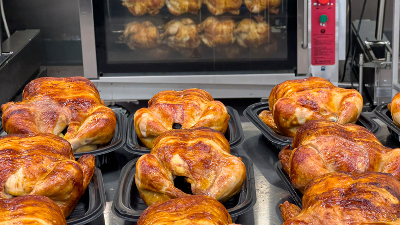 Several rotisserie chickens on counter and cooking on spit