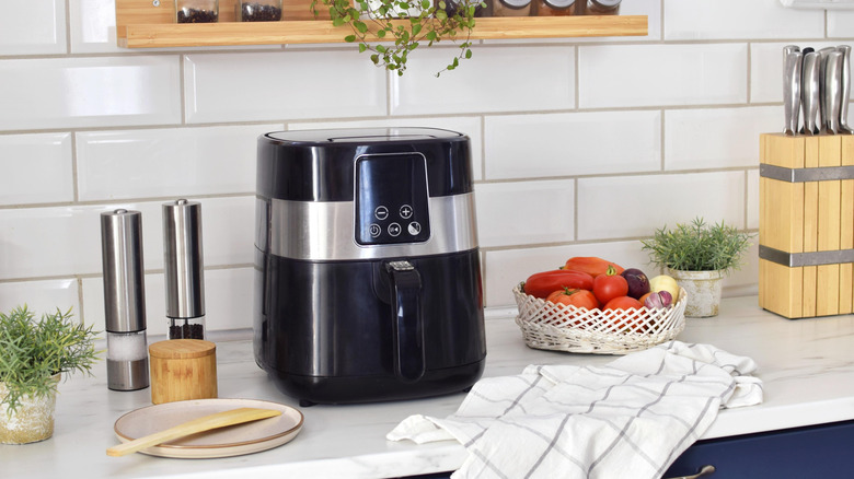 An air fryer on a kitchen counter next to kitchen equipment and ingredients