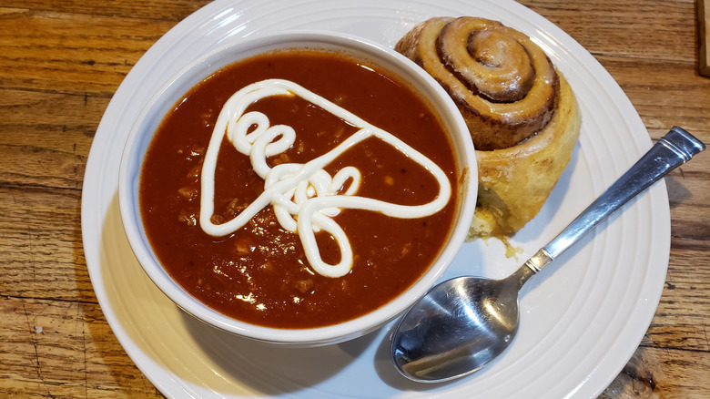 Chili and a cinnamon roll on a plate