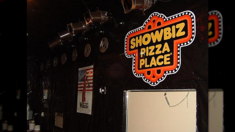 The interior of a Showbiz Pizza, with a sign for the restaurant on the wall