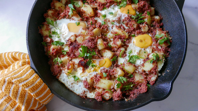 corned beef hash and eggs in skillet 