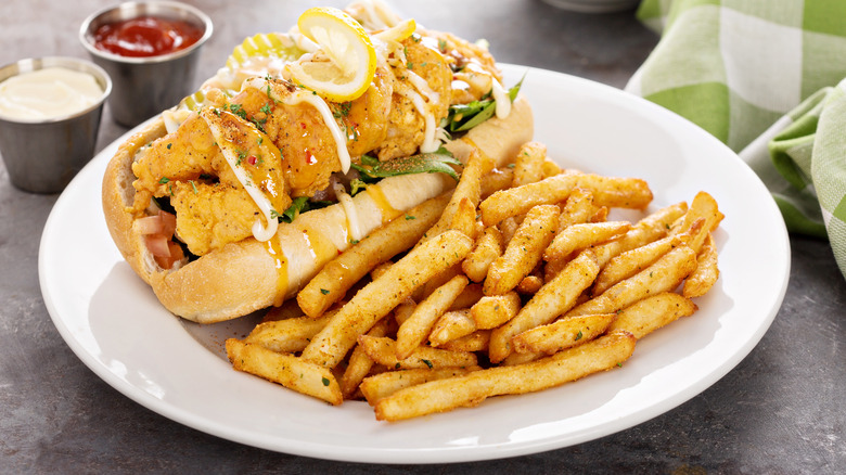 Shrimp po' boy with fries on white plate