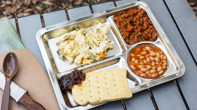 A meal made of military rations on a metal tray on an outdoor table