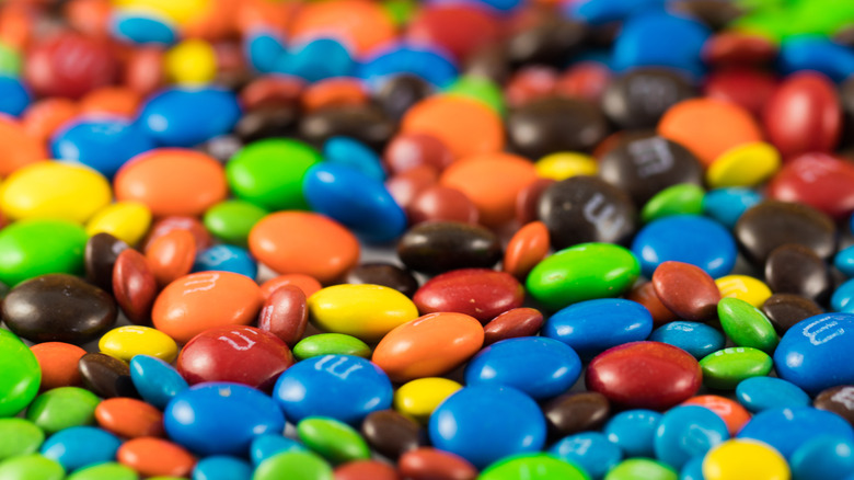 A close-up texture shot of colorful M&Ms in different sizes filling the frame