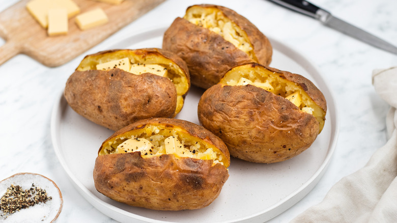 four baked potatoes on plate