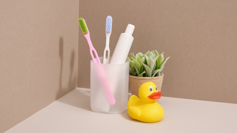Toothbrushes in a cup and rubber duck