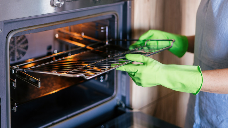 gloved hands taking grate out of oven