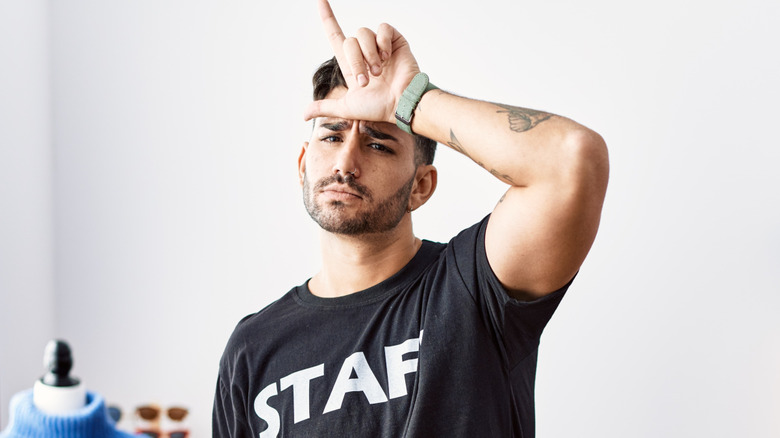 Man wearing a STAFF t-shirt giving a loser sign