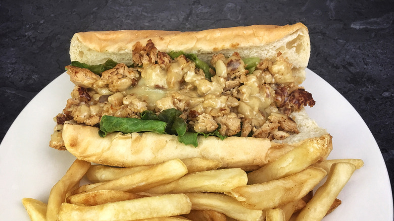 A chicken cheesesteak on a plate with fries