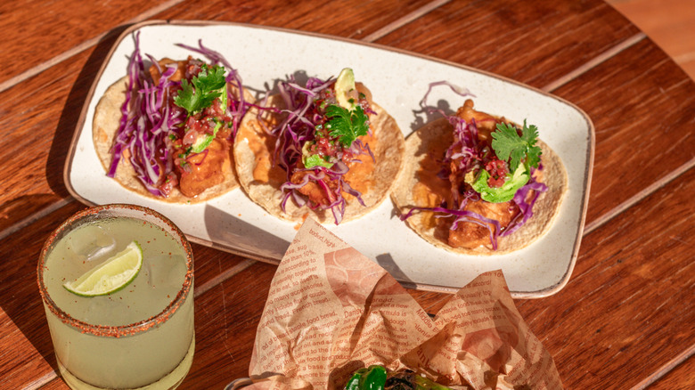 A serving of shrimp tacos with a margarita