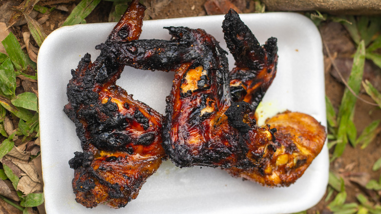 A white plate of burnt grilled chicken wings