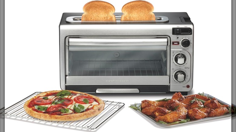 A toaster oven with two pieces of toast popping out of it and a pizza and chicken wings in front of it