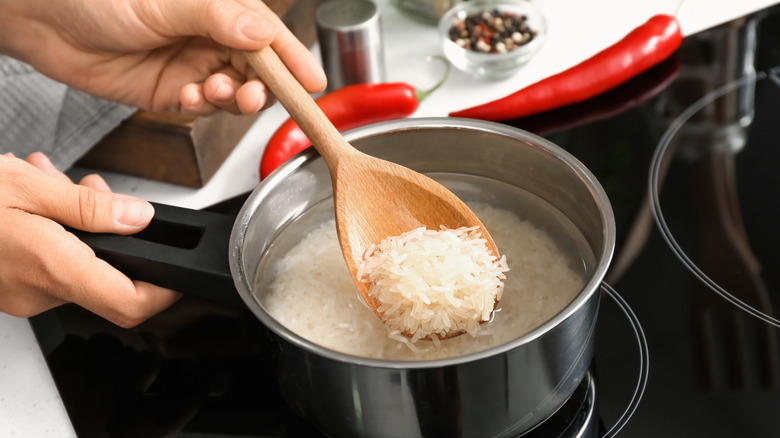 a person holding a spoon of rice over a pot