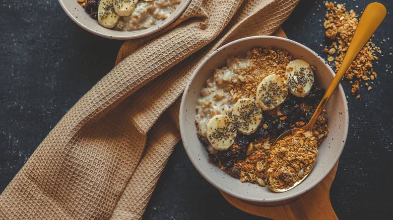Bowl of oatmeal with granola, bananas, raisins, and chia seeds