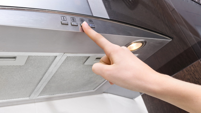 Person turning range hood's exhaust fan on high