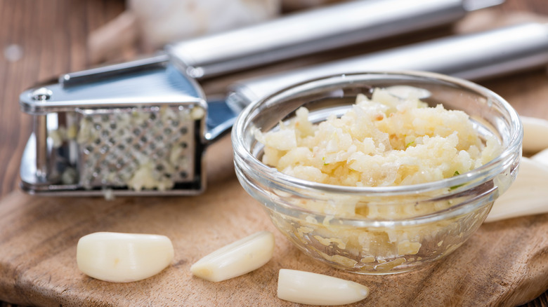 Garlic press with a bowl of garlic