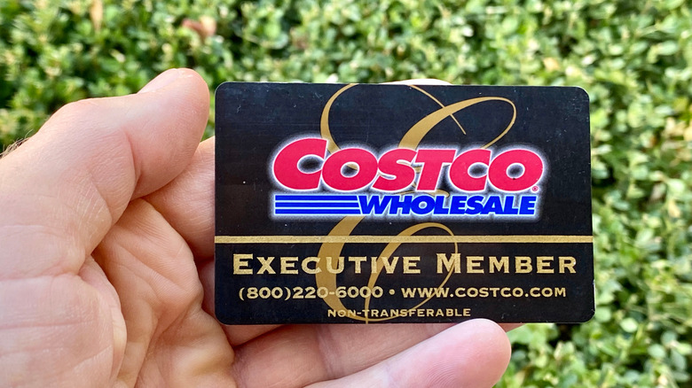 A close-up of a hand holding a Costco executive member card