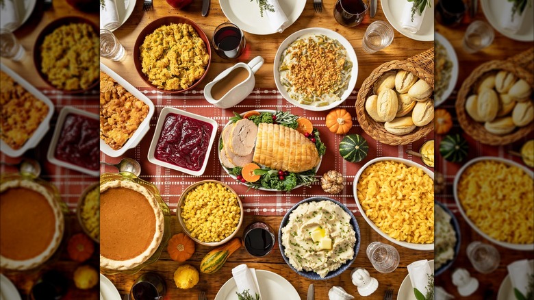 A full Thanksgiving spread with sliced turkey breast, mac and cheese, mashed potatoes, stuffing, pie, and more