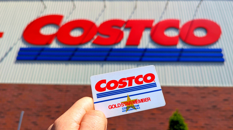 Costco membership card held in front of store sign