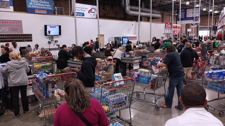 Costco shoppers stand in line to pay for their goods