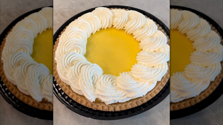 A large lemon custard pie with a thick ring of whipped topping