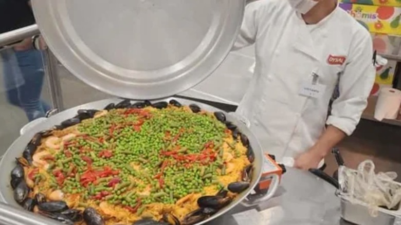 Cook opening up pan of paella