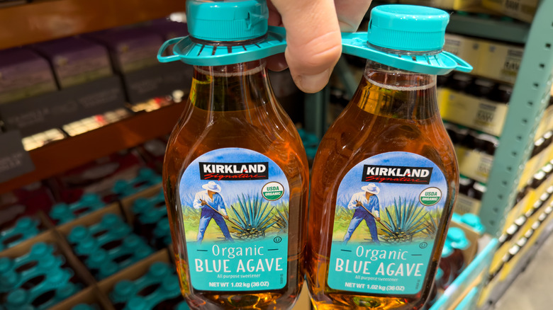shopper holding two pack of kirkland agave syrup