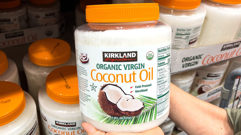 shopper holding jar of kirkland coconut oil