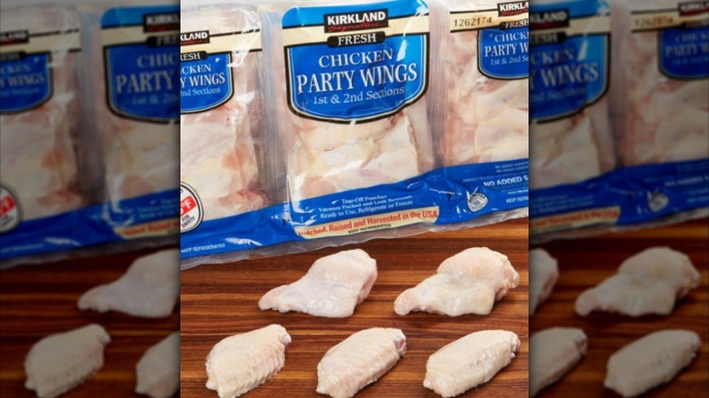 A package of Kirkland Signature party wings, with raw chicken wings sitting on a board