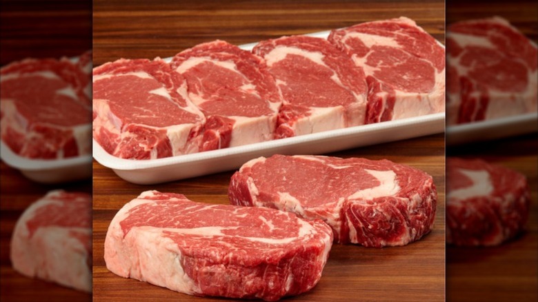 A package of Kirkland Signature ribeye with two steaks on a wooden board