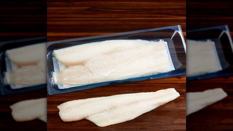 A package of raw Kirkland Signature Pacific cod on a wooden board