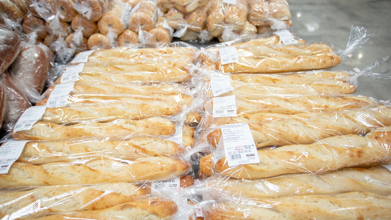 An array of baguettes in the Costco bakery, with bagels and bread in the background